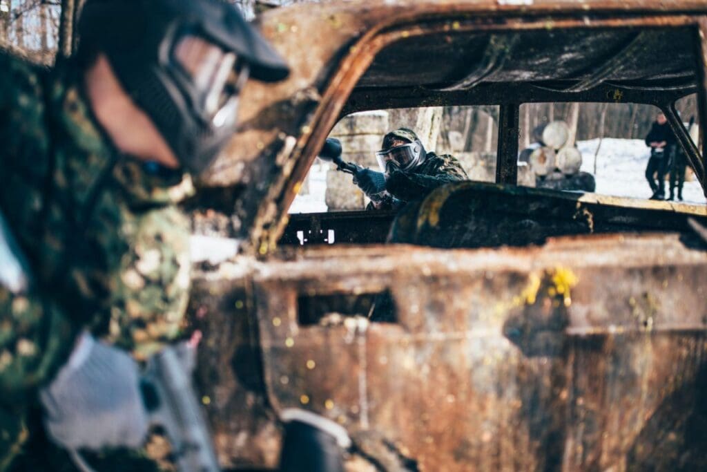paintball battle players fight around burned car winter forest paintballing extreme sport military game